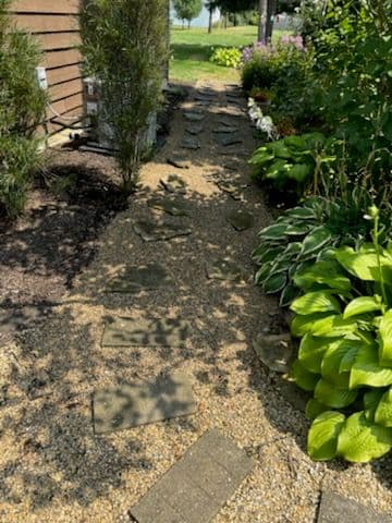 Garden pathway with stone steps, surrounded by lush greenery and colorful flowers.