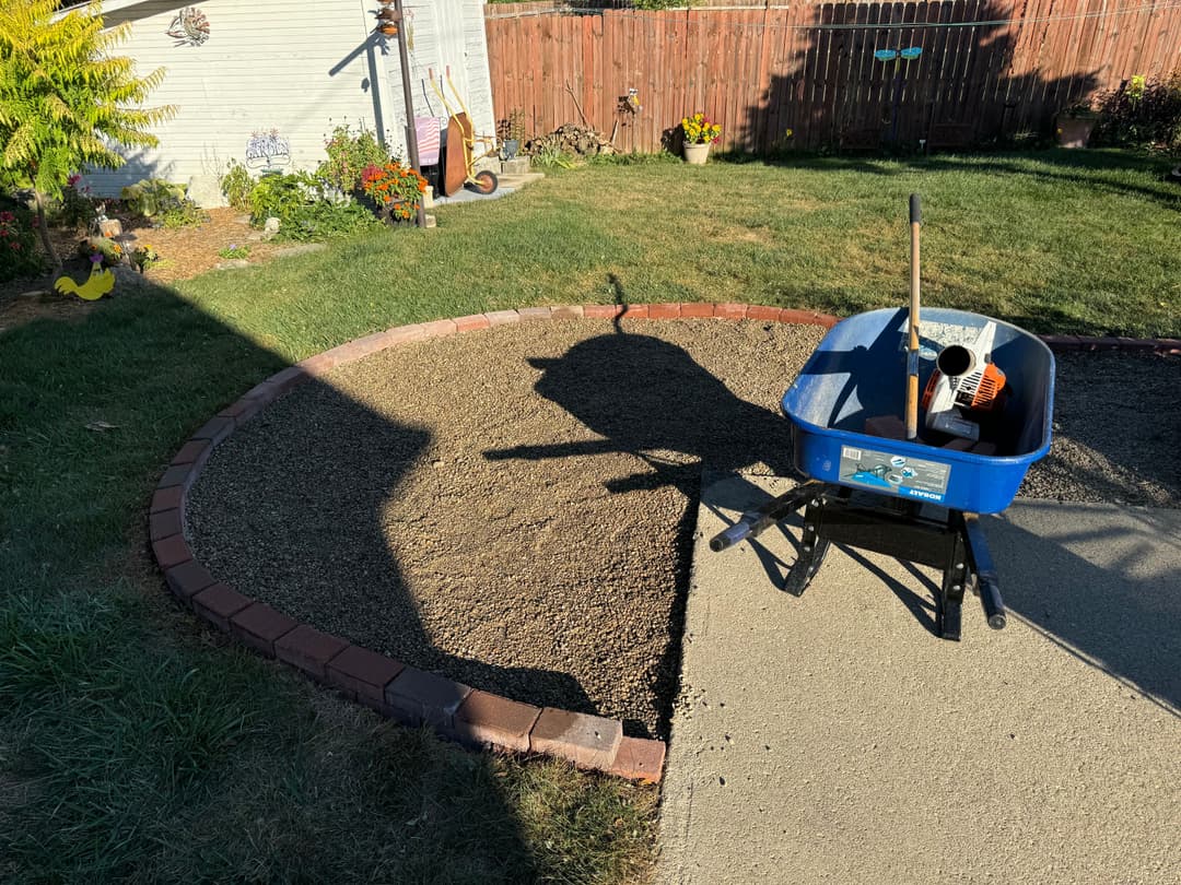 Garden landscape area being prepared with a wheelbarrow and stone edging in a backyard.